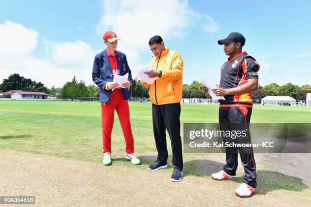 Captain Liam Roche of Zimbabwe, umpire Shozab Raza and captain Vagi Karaho of Papua New Guinea take part in the coin toss prior to the ICC U19...