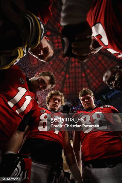 Quarterback Jake Fromm, tight end Miles McGinty and linebacker Jaden Hunter of the Georgia Bulldogs huddle together following the CFP National...
