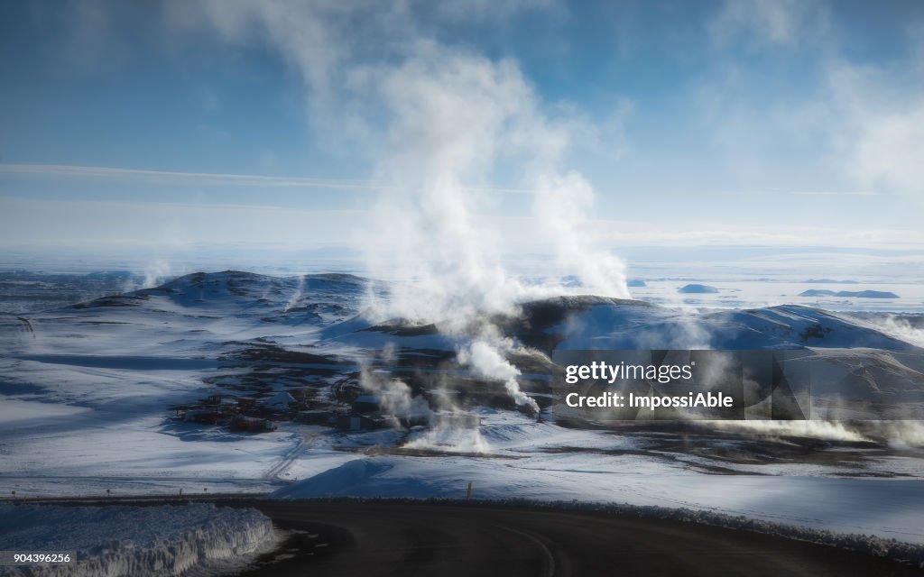 Kafla thermal energy with smoke from the crater above the lava field covered by snow in winter