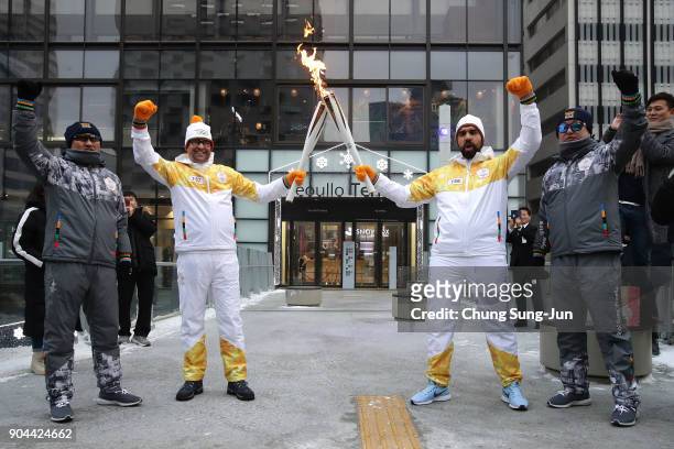Torch bearers hold the PyeongChang 2018 Winter Olympics torch during the PyeongChang 2018 Winter Olympic Games torch relay on January 13, 2018 in...