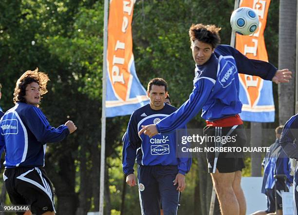 Paraguay's defender Julio Caceres heads the ball while teammates forward Nelson Haedo and goalkeeper Aldo Bobadilla look on during a training session...