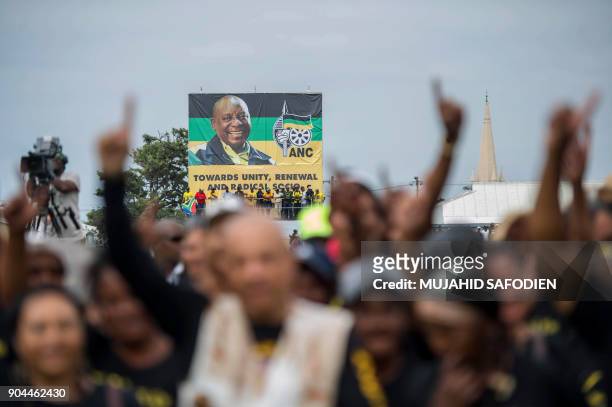 Supporters stand under a banner bearing a portrait of African National Congress President Cyril Ramaphosa during the ANC's 106th anniversary...