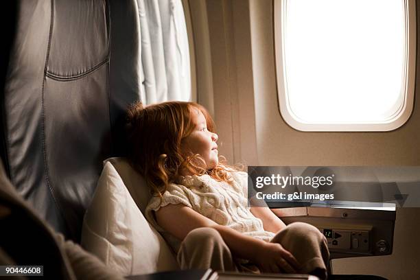 girl (2-3) looking out airplane window - flugzeugsitz stock-fotos und bilder