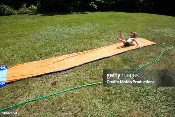 boy (4-5) on slip-n-slide - backyard water slide stock pictures, royalty-free photos & images