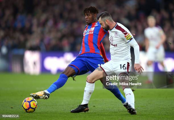 Wilfried Zaha of Crystal Palace controls the ball under pressure from Steven Defour of Burnley during the Premier League match between Crystal Palace...