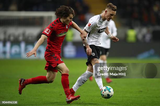 Caglar Soeyuencue of Freiburg runs with Marc Stendera of Frankfurt during the Bundesliga match between Eintracht Frankfurt and Sport-Club Freiburg at...