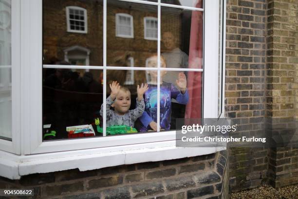 Young children view through their window as the three Straw Bears are led through the streets during the annual Whittlesea Straw Bear Festival parade...