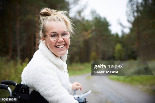 portrait of smiling young disabled woman sitting in wheelchair on road - autism adult stock pictures, royalty-free photos & images