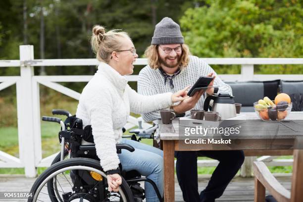young male caretaker and disabled woman using digital tablet in yard - physical disability stock pictures, royalty-free photos & images