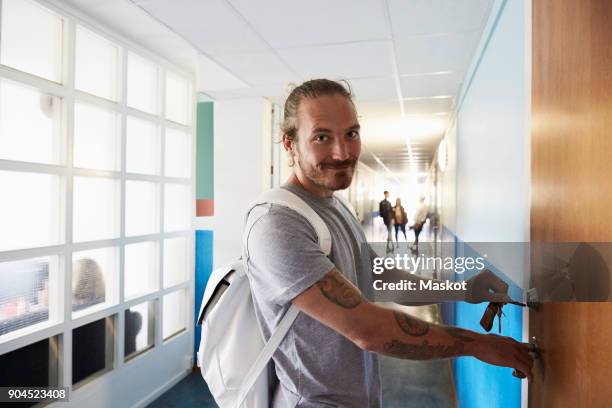 portrait of man opening door while students standing in corridor at university - open day 4 stock pictures, royalty-free photos & images