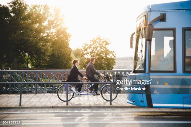 full length side view of senior couple riding tandem bike on bridge - stockholm imagens e fotografias de stock