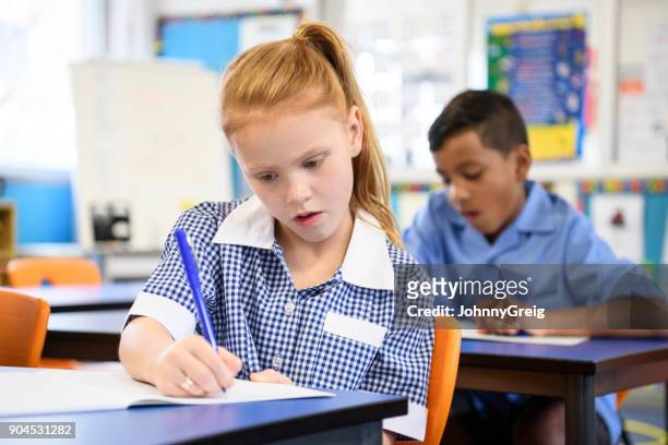 school girl with red hair writing in book and concentrating - gingham stock pictures, royalty-free photos & images