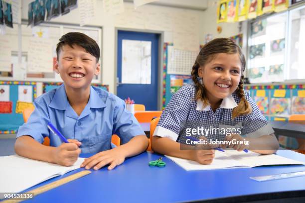 two school children sitting next to each other in classroom and smiling - native korean stock pictures, royalty-free photos & images