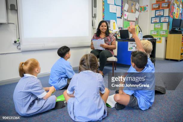 schoolkinderen zittend op de vloer van de klas luisteren naar hun leraar - small child sitting on floor stockfoto's en -beelden