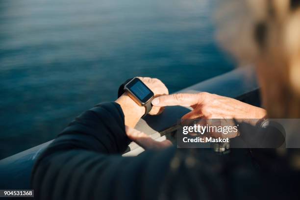 cropped image of senior woman using smart watch at bridge railing - silver surfer stock pictures, royalty-free photos & images