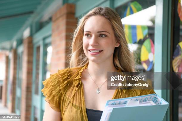 young schoolteacher smiling and looking away holding ring binder - teacher with folder stock pictures, royalty-free photos & images