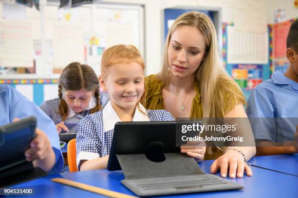 teacher helping young girl using digital tablet in classroom - school australia stock pictures, royalty-free photos & images