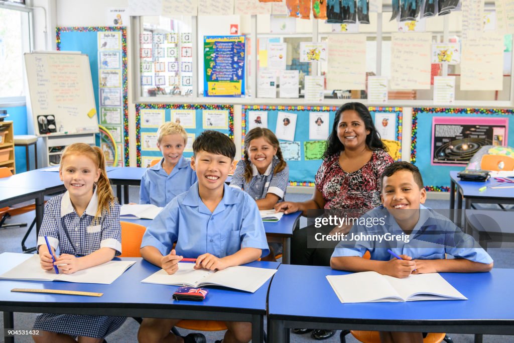 Gut erzogene Kinder sitzen an ihrem Schreibtisch mit ihrem Lehrer