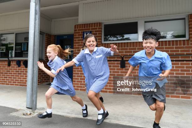 three children running out from school across playground laughing - native korean stock pictures, royalty-free photos & images