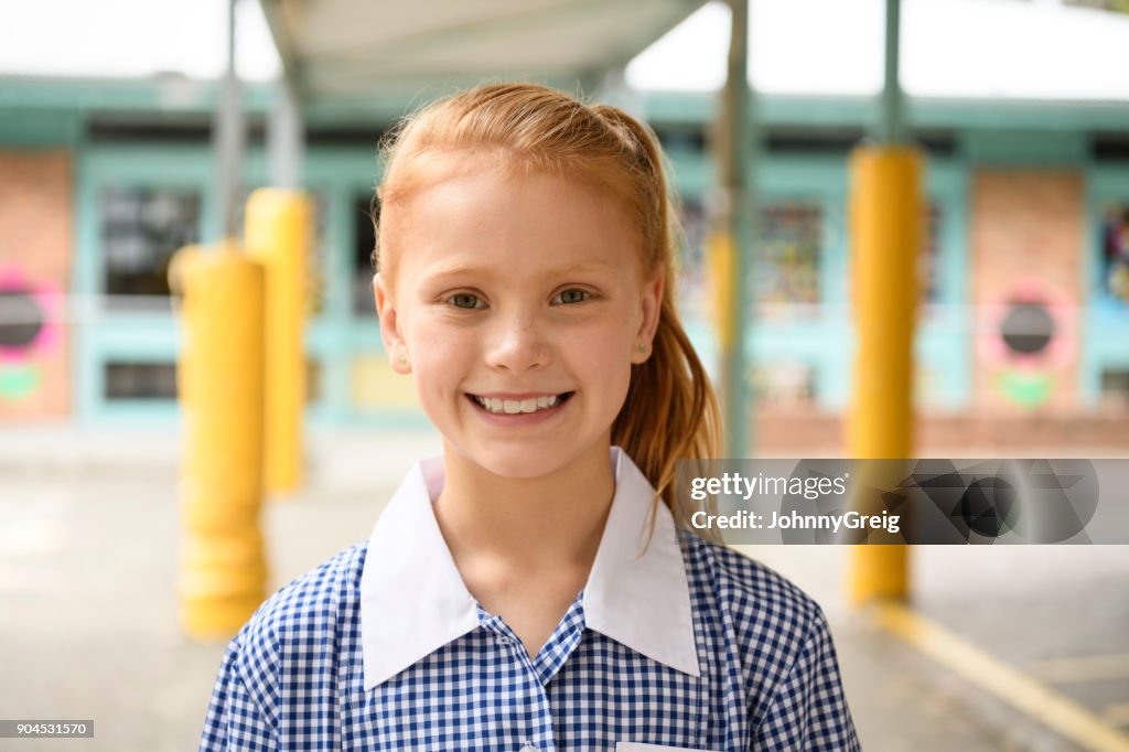 Portrait of cheerful girl with red hair smiling towards camera