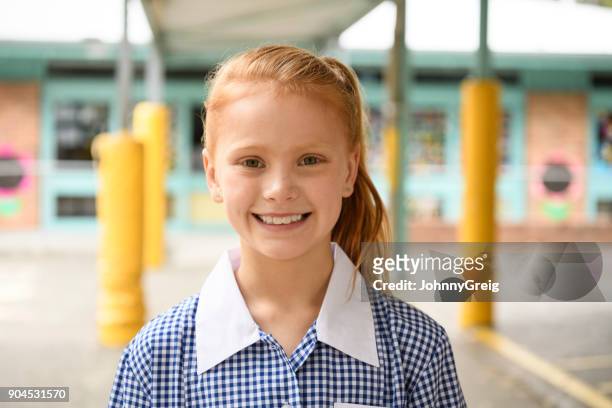 portrait of cheerful girl with red hair smiling towards camera - school uniform stock pictures, royalty-free photos & images