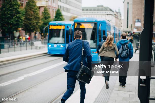rear view of businessman running towards cable car on street in city - urgenza foto e immagini stock