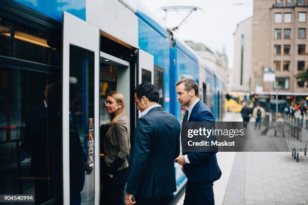 mature business colleagues entering cable car in city - straßenbahn stock-fotos und bilder