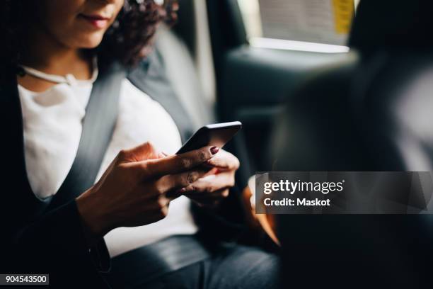 midsection of businesswoman using smart phone while sitting in taxi - cellphone car stock pictures, royalty-free photos & images