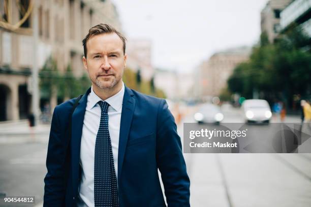 portrait of confident mature businessman walking on street in city - man walking in city stock pictures, royalty-free photos & images