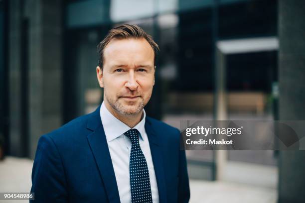 portrait of confident mature businessman standing in city - blue suit stock pictures, royalty-free photos & images