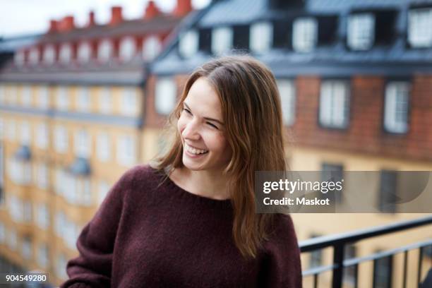 smiling young woman standing in balcony at rental apartment - stockholm city stock-fotos und bilder