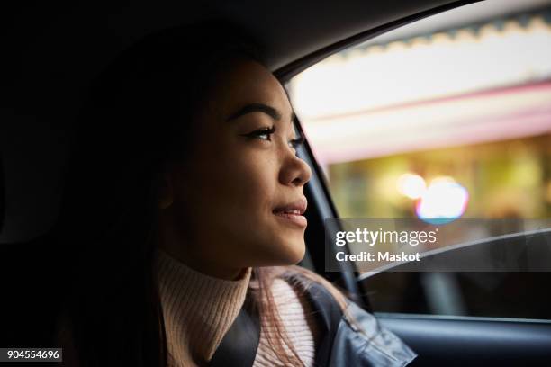 thoughtful young woman looking through window while sitting in car - taxi bildbanksfoton och bilder