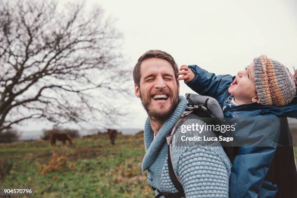 a father laughs share a funny moment whilst walking in the countryside - baby pullover stockfoto's en -beelden