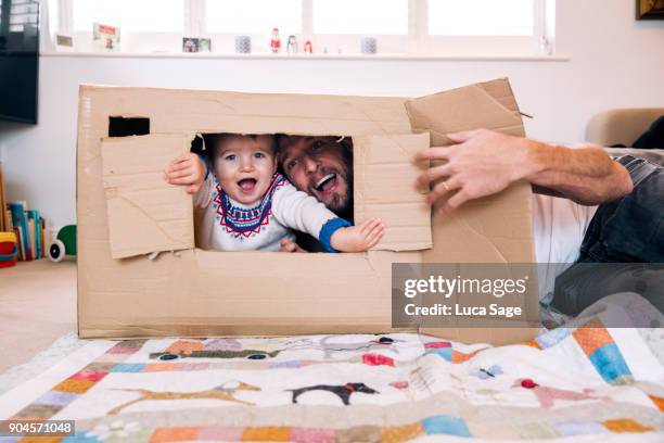 father and son playing at home with a cardboard box - baby playing stock-fotos und bilder