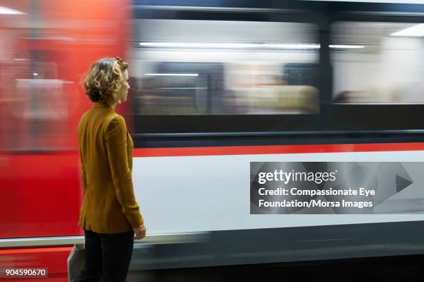 businesswoman looking at subway train - vorbeigehen stock-fotos und bilder