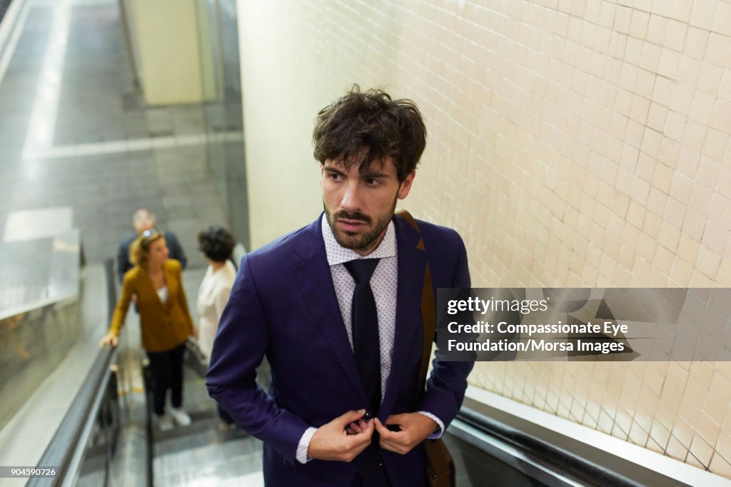 Businessman on escalator in train station