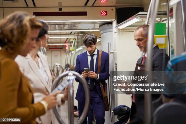 businessman using cell phone on subway train - subway stock-fotos und bilder