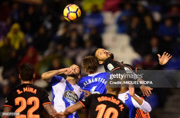 Valencia's Argentinian defender Ezequiel Garay jumps for the ball with Deportivo La Coruna's Spanish defender Raul Albentosa and Deportivo La...