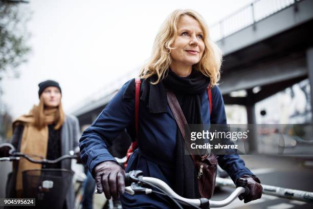 rijpe vrouw fietsten glimlachend met vriend - middle aged woman winter stockfoto's en -beelden