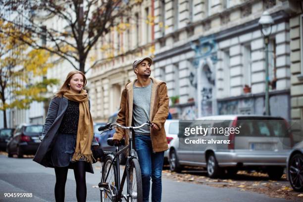 friends walking with cycle on street during winter - city life stock pictures, royalty-free photos & images