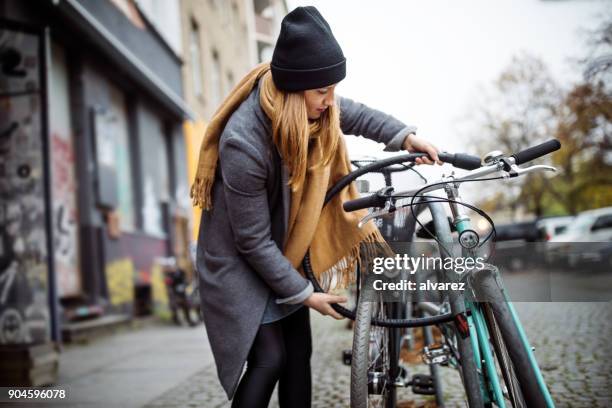 vélo de verrouillage jeune femme dans la ville au cours de l’hiver - fermer à clef photos et images de collection