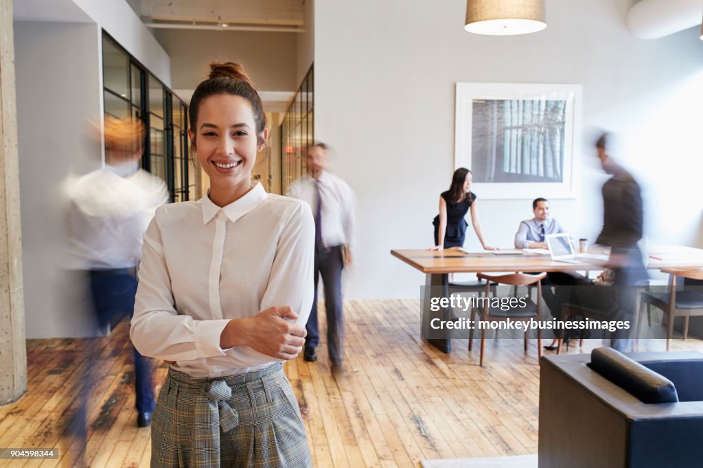 Retrato de uma jovem mulher branca em um ambiente de trabalho moderno ocupado