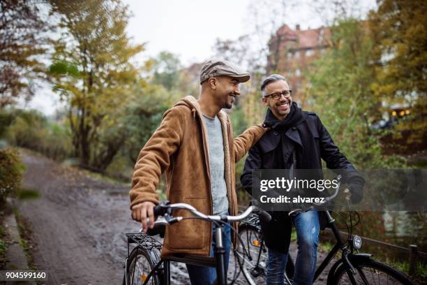 happy friends with bicycles walking by plants - winter cycling stock pictures, royalty-free photos & images