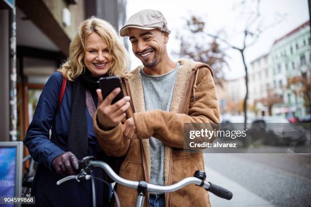 téléphone intelligent de heureux homme montrant à un ami - berlin stock photos et images de collection