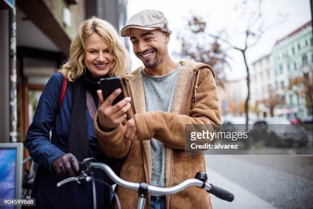happy man showing smart phone to friend - mid adult men stock pictures, royalty-free photos & images