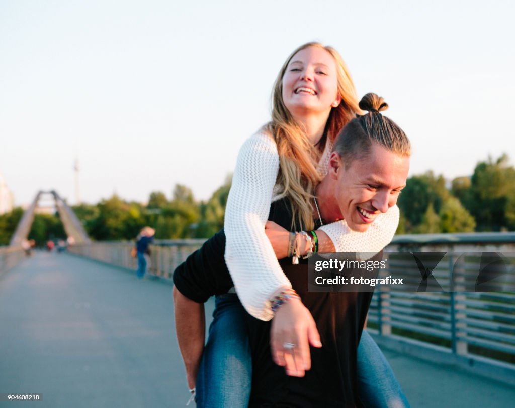 Friendship: young couple has fun with piggyback, summer in Berlin