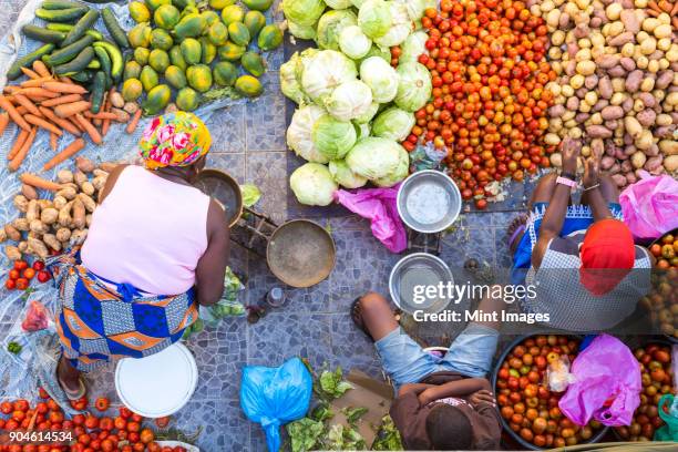 high angle view of vendors selling a selection of fresh vegetables on a street market. - áfrica del oeste fotografías e imágenes de stock