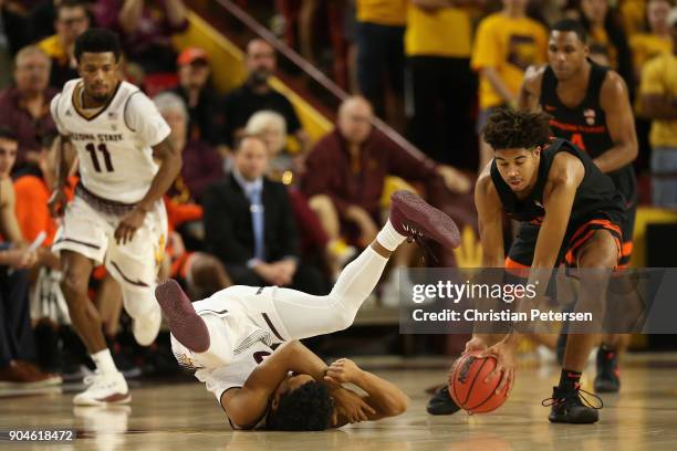 Tra Holder of the Arizona State Sun Devils falls to the court with an injury as Ethan Thompson of the Oregon State Beavers controls the ball during...