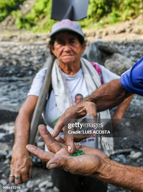 Emerald seeker Blanca Biutrago looks on as another seeker shows some of the green gems found in the Las Animas river close to an emerald mine in the...