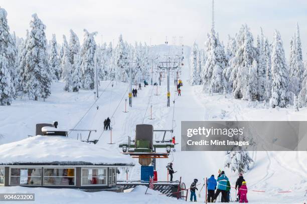 group of people near a ski lift in forest with snow-covered trees. - winter sport stock pictures, royalty-free photos & images